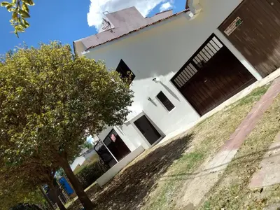 a white house with a tree in front of it at Dúplex frente al río en Playas de Oro in Villa Carlos Paz
