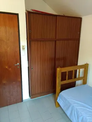 a bedroom with a bed and a wooden closet at Dúplex frente al río en Playas de Oro in Villa Carlos Paz