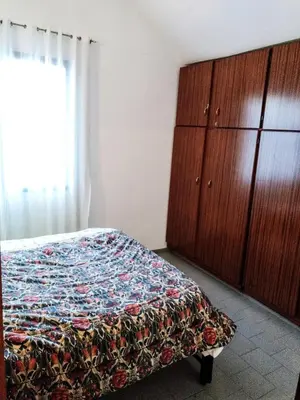 a bedroom with a bed and wooden cabinets and a window at Dúplex frente al río en Playas de Oro in Villa Carlos Paz