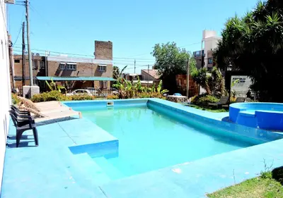 a blue swimming pool with a chair next to it at DEPARTAMENTO MAGNET in Villa Carlos Paz