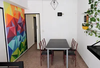 a table and chairs in a room with a colorful painting at DEPARTAMENTO MAGNET in Villa Carlos Paz