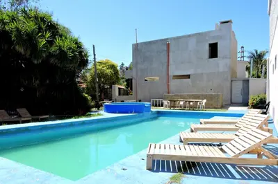a swimming pool with chaise lounges and chairs at DEPARTAMENTO MAGNET in Villa Carlos Paz