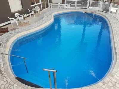 a large blue swimming pool with chairs and tables at Hotel Brisas in Villa Carlos Paz