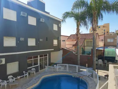 a swimming pool in front of a building with palm trees at Hotel Brisas in Villa Carlos Paz