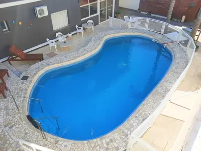 a large swimming pool with blue water at Hotel Brisas in Villa Carlos Paz