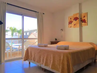 a bedroom with a large bed and a balcony at Hotel Brisas in Villa Carlos Paz