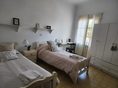 a bedroom with two beds and a table and a window at Rivahome in Cordoba