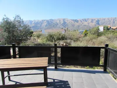 a wooden bench on a balcony with mountains in the background at Chalet Individual Maiten 1 in Merlo