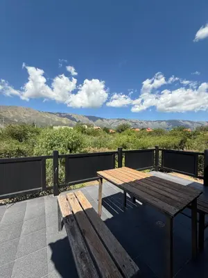 a wooden table and bench on a balcony with mountains at Chalet Individual Maiten 1 in Merlo