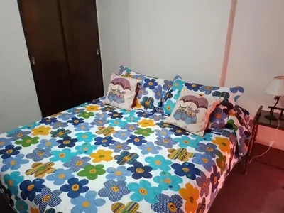 a bed with a floral comforter and pillows on it at Corro temporal in Cordoba