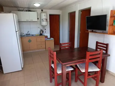 a kitchen with a wooden table and chairs and a refrigerator at Cabañas Dayma in Trapiche