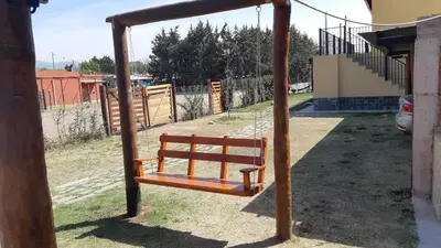 a wooden swing in a yard next to a house at Cabañas Dayma in Trapiche