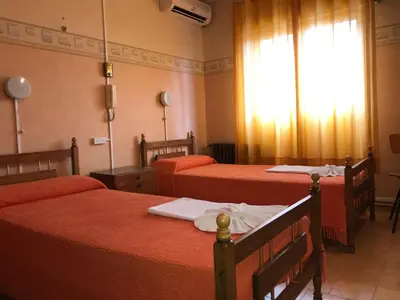 a room with three beds with red sheets and a window at HOTEL ESCORIAL in Villa Carlos Paz