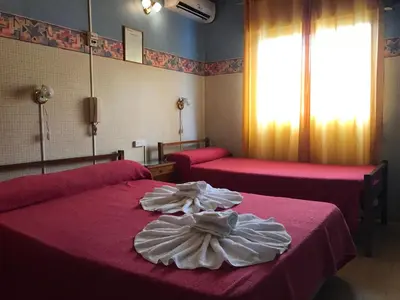 a hotel room with two beds with red sheets at HOTEL ESCORIAL in Villa Carlos Paz