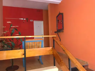 a room with orange walls and a staircase with a mirror at HOTEL ESCORIAL in Villa Carlos Paz