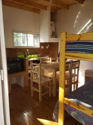 a bedroom with a bunk bed and a kitchen with a table at Las Zarinas 3 in Trapiche