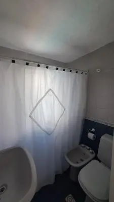 a bathroom with a white shower curtain and a toilet at Casa Villa Naturaleza in Villa Rumipal