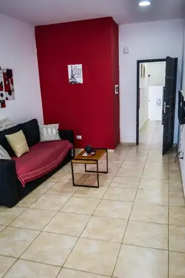a living room with a couch and a red wall at Amplio Dpto s/Av Rafael Nuñez - cerro de las rosas in Cordoba
