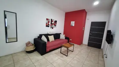 a living room with a couch and a red wall at Amplio Dpto s/Av Rafael Nuñez - cerro de las rosas in Cordoba