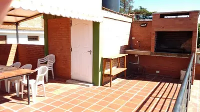 a patio with a table and chairs and a building at Casas villa suiza con terraza in Villa Carlos Paz