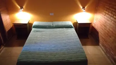a bed in a room with two lights on the wall at Casas villa suiza con terraza in Villa Carlos Paz