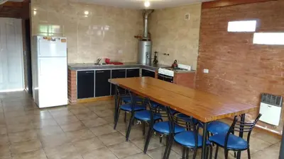 a kitchen with a wooden table and blue chairs at Casas villa suiza con terraza in Villa Carlos Paz