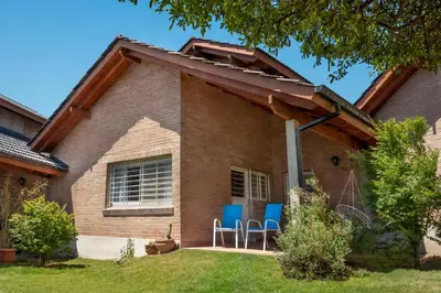 a house with awning and blue chairs on the porch at Casa Arboles De Tala con parque amplio in Villa General Belgrano