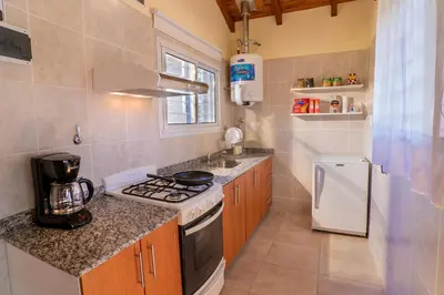 a small kitchen with a stove and a refrigerator at Casa Arboles De Tala con parque amplio in Villa General Belgrano