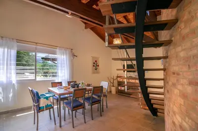 a dining room with a table and chairs and a spiral staircase at Casa Arboles De Tala con parque amplio in Villa General Belgrano
