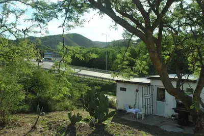 a small white house with a tree and a highway at Cabaña 