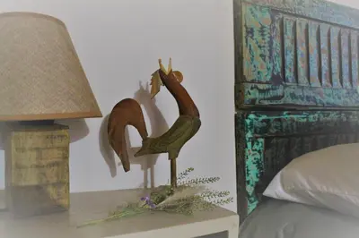 a wooden bird statue on a table next to a bed at Pequeña Polonia-Lodge & Cabañas in Los Reartes
