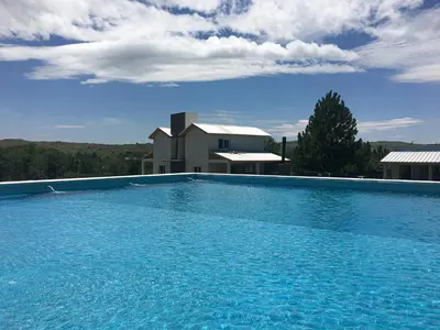 a large blue swimming pool in front of a house at Cabañas Sonnenblumen in Potrero de Garay