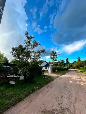 an empty dirt road with a house in the distance at Aguila Blanca in Mina Clavero