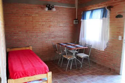 a bedroom with a red bed and a table with chairs at Aguila Blanca in Mina Clavero