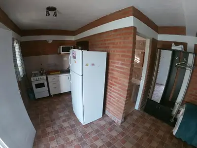 a kitchen with a white refrigerator and a brick wall at Aguila Blanca in Mina Clavero