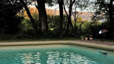 a pool of water in a yard with mountains in the background at Cuatrovientos Hostería in San Javier