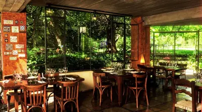a restaurant with wooden tables and chairs and windows at Cuatrovientos Hostería in San Javier