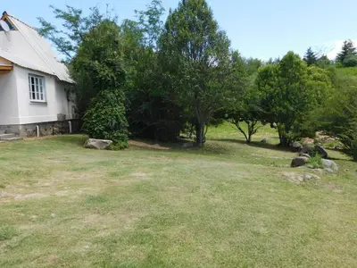 a yard next to a white house with trees at 7 esencias in Villa Yacanto