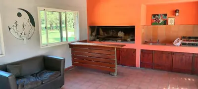 a kitchen with orange walls and a couch and a fireplace at Cabañas UN LUGAR in Villa General Belgrano
