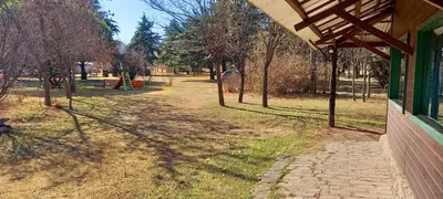a view of a park with trees and a building at Cabañas UN LUGAR in Villa General Belgrano