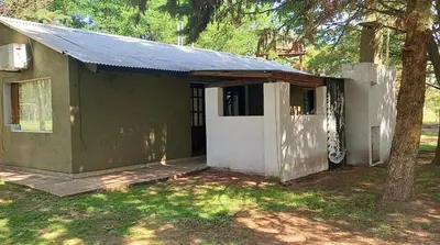 a green building with a door and a tree at Cabañas UN LUGAR in Villa General Belgrano