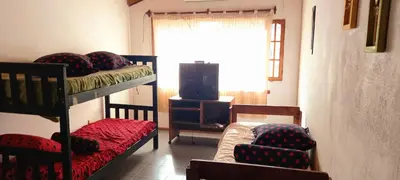 a room with bunk beds and a tv and a chair at Cabañas UN LUGAR in Villa General Belgrano