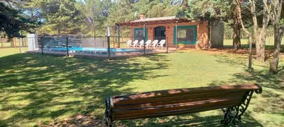 a park bench sitting in the grass next to a house at Cabañas UN LUGAR in Villa General Belgrano