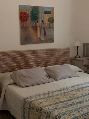a bed in a bedroom with a painting on the wall at Elportal in Alta Gracia