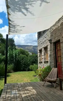 a wooden deck with a bench and a stone building at Aloja Merlo - Conectá con la naturaleza en un ambiente único in Merlo
