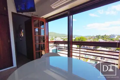 a table in a room with a view of a balcony at Depto Las Heras in Villa Carlos Paz