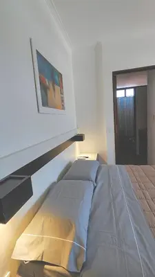 a bed in a white room with a picture on the wall at Depto Las Heras in Villa Carlos Paz