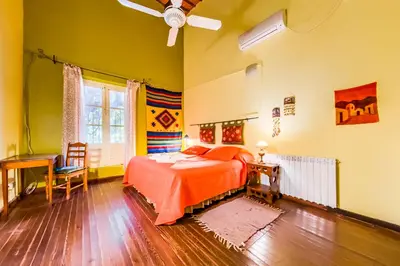 a bedroom with a bed with orange sheets and a fan at Posada El Pucara in San Javier