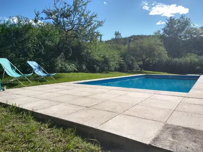 two lawn chairs sitting next to a swimming pool at El diquecito duplex in Casa Bamba