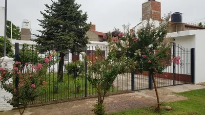 a wrought iron fence with two trees in a yard at Casa Kassel in Villa Cura Brochero